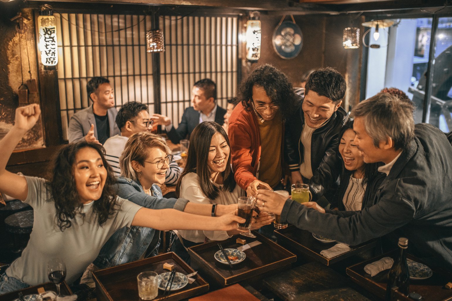 Fun-Loving Friends Toasting at Sushi Bar in Tokyo Izakaya